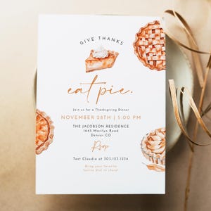 May include: A white invitation card with brown text that reads "Give Thanks eat pie." The invitation is for a Thanksgiving dinner on November 28th at 5:00 PM at The Jacobson Residence, 1645 Marilyn Road, Denver CO. The invitation includes a phone number to RSVP and asks guests to bring their favorite festive dish to share. The invitation is decorated with watercolor illustrations of pie.