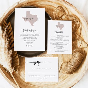 May include: Wedding invitation suite featuring a Texas-shaped graphic with the words "Houston here." The suite includes an invitation, details card, and RSVP card, all with elegant typography. The cards are arranged on a wooden tray.