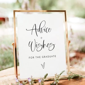 May include: A gold-framed sign with white paper inside. The sign says "Advice + Wishes for the Graduate" with a small heart at the bottom.