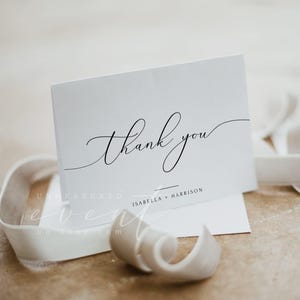 May include: White thank you card with black calligraphy that says "thank you" and the names "Isabella + Harrison" printed below.