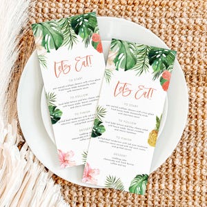 May include: Two tropical-themed menu cards with green leaves, pink flowers, and the text "Let's Eat!". The menus list dishes like scallops, beef tenderloin, and cheesecake, presented on a white plate.