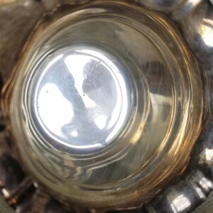 K&ouml;nnte beinhalten: Eine silberne Kanne mit geriffeltem Rand und gl&auml;nzendem, reflektierendem Innenraum. Die Kanne ist leer und scheint aus Metall zu sein.
