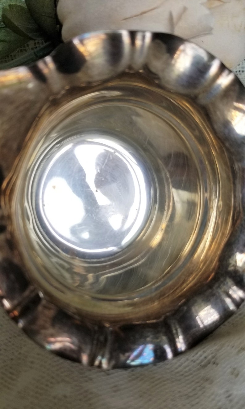 K&ouml;nnte beinhalten: Eine silberne Kanne mit geriffeltem Rand und gl&auml;nzendem, reflektierendem Innenraum. Die Kanne ist leer und scheint aus Metall zu sein.