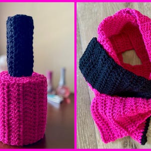 May include: A pink and black crocheted scarf. The scarf is made from two different colours of yarn, with a black section in the middle and pink sections on either side. The scarf is folded in half and the ends are tied together.