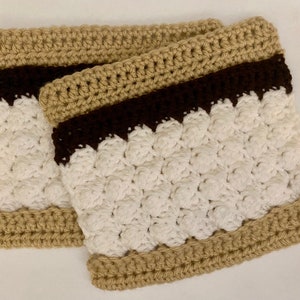 May include: Two crocheted leg warmers with a brown, white and tan striped pattern. The leg warmers are made with a textured stitch.
