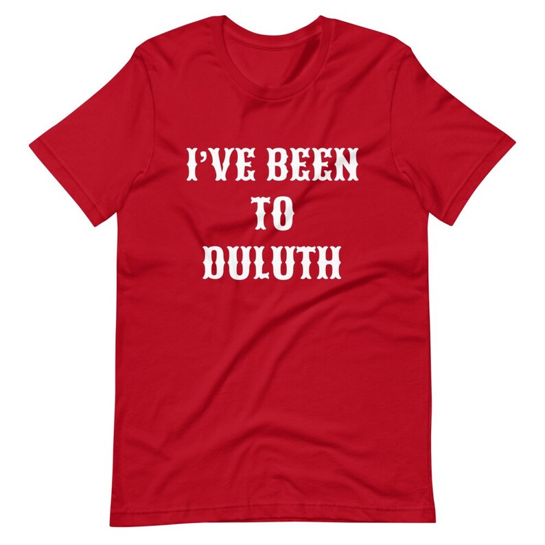 以下が含まれることがあります： 白い文字で「I'VE BEEN TO DULUTH」と書かれた赤い半袖Tシャツです。
