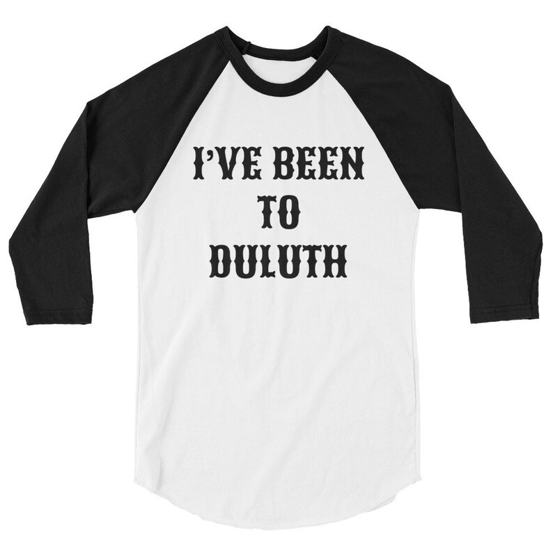 以下が含まれることがあります： 白と黒のベースボールTシャツに「I've Been To Duluth」という黒い文字がプリントされています。