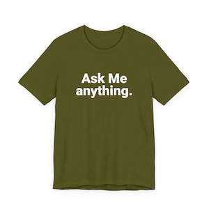 Può includere: T-shirt verde oliva con la scritta bianca "Ask Me anything." sul davanti. La maglietta ha maniche corte e scollo tondo.