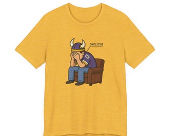 May include: Mustard yellow t-shirt with a cartoon illustration of a person wearing a Viking helmet, sitting in a brown armchair, with their face in their hands. The word "SKOLIOSIS" is written above the person.