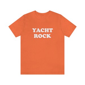 Puede incluir: Camiseta naranja de manga corta con el texto "YACHT ROCK" en blanco.