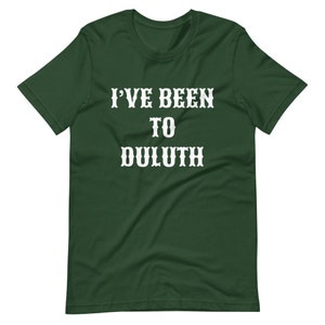 以下が含まれることがあります： 「I'VE BEEN TO DULUTH」という白い文字が書かれた濃い緑色のTシャツです。