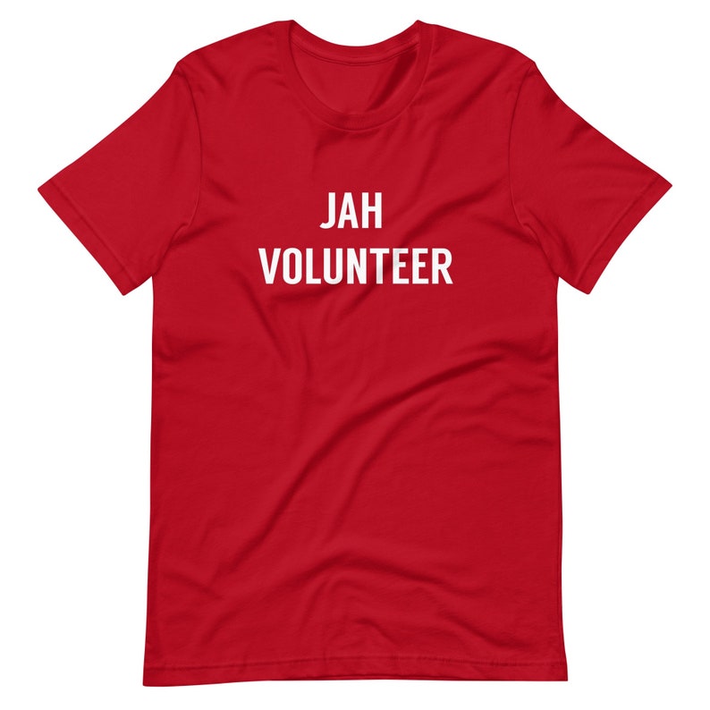 May include: Red short-sleeved t-shirt with white text that reads "JAH VOLUNTEER".