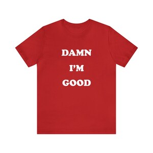 May include: Red short-sleeved t-shirt with white text that reads "DAMN I'M GOOD".
