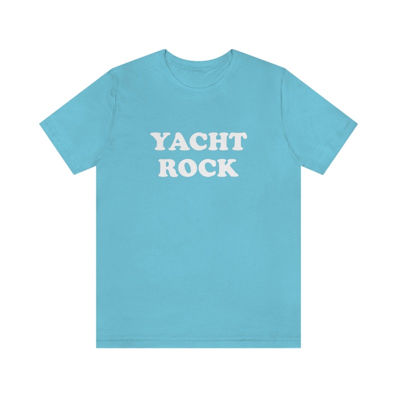Puede incluir: Una camiseta azul claro con el texto "YACHT ROCK" impreso en blanco.