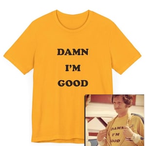 May include: A yellow t-shirt with the text "DAMN I'M GOOD" printed on it. The shirt is shown on a model wearing a similar shirt.