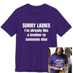 Op de afbeelding: Een paars t-shirt met de tekst "SORRY LADIES I'm already like a brother to someone else" in het wit. De afbeelding bevat ook een kleinere afbeelding van een persoon die hetzelfde shirt draagt.