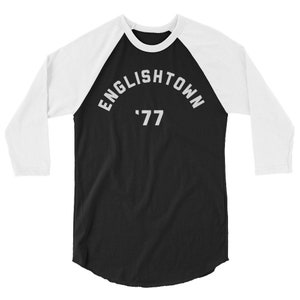 May include: Black and white baseball style t-shirt with a white three-quarter length sleeve. The shirt has the text "ENGLISHTOWN '77" printed on the front in a white arc.