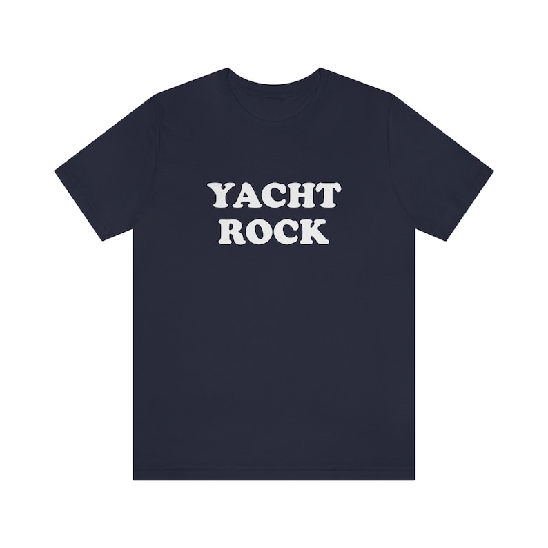 Puede incluir: Una camiseta azul marino con el texto "YACHT ROCK" impreso en blanco.