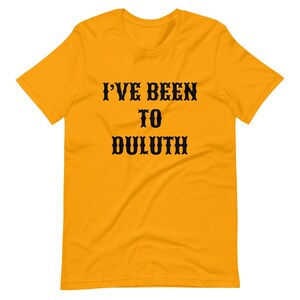 以下が含まれることがあります： 黒い文字で「I'VE BEEN TO DULUTH」と書かれた黄色の半袖Tシャツです。