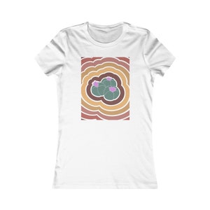 May include: A white t-shirt with a graphic of three green cactus plants with pink flowers in the center of a swirling pattern of brown, orange, and pink.