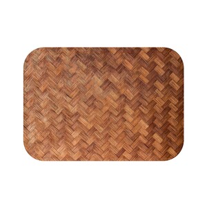 May include: Rectangular woven placemat with rounded corners. The placemat features a repeating pattern of interwoven brown and tan strips, creating a textured surface. The design is reminiscent of traditional basketry.
