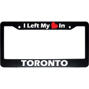 May include: Black license plate frame with the text "I Left My ❤️ In" above and "TORONTO" below in white letters. A red heart graphic is between "My" and "In".
