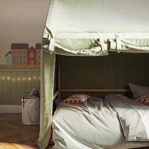 Puede incluir: Un edred&oacute;n a rayas verdes y blancas con un dosel blanco sobre la cama. La cama est&aacute; en una habitaci&oacute;n con suelo de madera y una pared verde. Hay luces de cadena en la pared y una peque&ntilde;a cesta con un animal de peluche dentro.