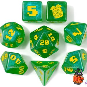 May include: A set of seven green and gold dice with a pineapple design on one die and the text "RGC" on the pineapple. The dice are translucent and have a glittery finish.