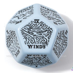 May include: A light blue six-sided dice with black ink illustrations of different weather conditions. The dice has the numbers I through VI on each side. The sides show "Rain", "Overcast", "Windy", "Showers", "Cloudy", and "Fog".