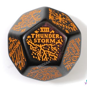 May include: A black and orange eight-sided die with the words "Thunder Storm" and Roman numerals "VIII" on one side. The other sides have the words "Hailstorm", "Blizzard", "Tornado", "Blinding Fog", "Eruption", and "Volcano".