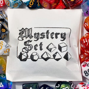 May include: A white paper bag with the words "Mystery Set" in a decorative font, surrounded by various dice in different colors and styles. The dice are scattered around the bag, creating a colorful and engaging display.