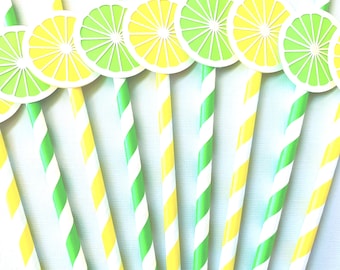 May include: A collection of drinking straws featuring diagonal green and white or yellow and white stripes, each topped with a circular paper cutout depicting a sliced lemon or lime in vibrant yellow and green hues arranged in a fan pattern.