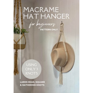 May include: A white macrame hat hanger with a hat hanging on it. The hanger is made with three knots: lark's head, square, and gathering knots. The text on the image reads "Macrame Hat Hanger for beginners Pattern Only Using Only 3 Knots Lark's Head, Square & Gathering Knots".