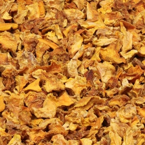 May include: Dried mango pieces, a close-up of a pile of dried mango slices, the mango pieces are a bright orange color and have a slightly translucent appearance.