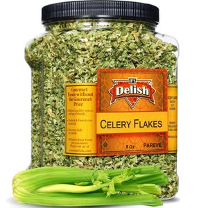 May include: A clear plastic jar filled with dried celery flakes. The jar has a yellow label with the text "It's Delish Celery Flakes 5 oz Pareve". A bunch of fresh celery stalks are in the foreground.
