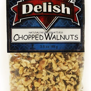 May include: A clear plastic bag filled with chopped walnuts. The bag has a blue and gold label that reads "It's Delish" and "Chopped Walnuts". The label also states "Natural! No Preservatives!" and "3.5 oz 99g".