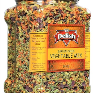 May include: A clear plastic jar filled with a mix of dried vegetables. The label reads "It's Delish Garden Dried Vegetable Mix 24 oz" and features a red and gold design. The label also states "Gourmet Foods without the Gourmet Price".