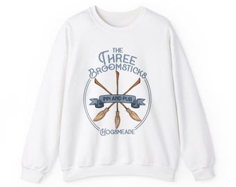 May include: White sweatshirt with a blue and brown graphic of the Three Broomsticks Inn and Pub from the Harry Potter series. The graphic includes the text "The Three Broomsticks Inn and Pub Hogsmeade".