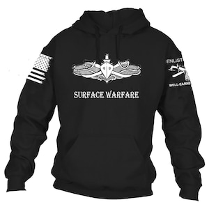 May include: Black hooded sweatshirt with white graphics. Features an American flag on the left sleeve and a ship emblem with the text "SURFACE WARFARE" on the front. The right sleeve has the text "ENLIST" and "WELL-EARNED".
