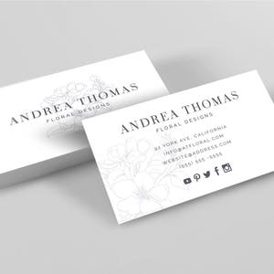 May include: White business card with the text "ANDREA THOMAS FLORAL DESIGNS" and a floral design. The card also includes contact information, a website address, and social media icons.
