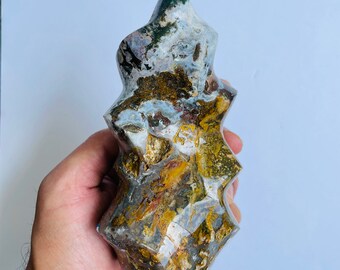 May include: A multi-faceted, green, brown, and white agate crystal point with a unique, pointed shape.