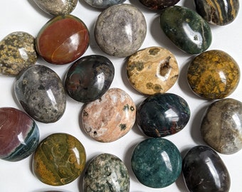 May include: A collection of 20 tumbled stones in various colours and patterns, including green, brown, black, white, and red. The stones are smooth and polished, and they are arranged in a random pattern on a white background.