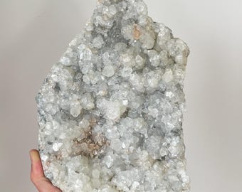 May include: A large, white, crystal cluster with a rough, natural texture. The cluster is composed of many small, clear crystals that are tightly packed together. The crystals have a slightly iridescent sheen.
