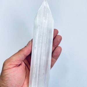 May include: A white selenite wand with a pointed tip. The wand is smooth and has a natural, striated texture.