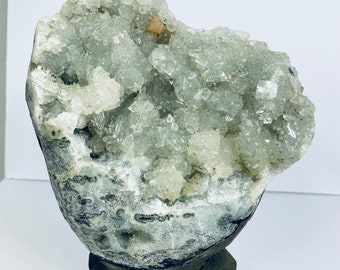 May include: A geode with a rough exterior and a hollow interior filled with clear, sparkling crystals. The geode is mounted on a wooden base.