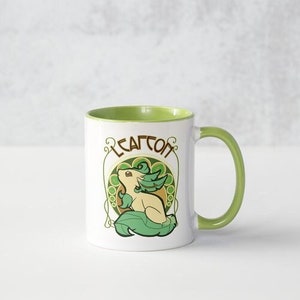 Peut inclure: Une tasse en céramique blanche avec un bord et une poignée verts. La tasse présente une illustration de dessin animé d'une créature verte et jaune avec le mot "Leafeon" imprimé au-dessus.