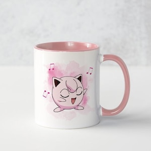 May include: A white ceramic mug with a pink rim and handle. The mug features a pink and white watercolor design of a cartoon pink Pokemon character singing with musical notes.
