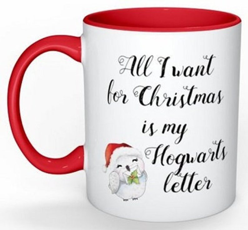 Puede incluir: Taza de cer&aacute;mica blanca con borde y asa rojos. La taza tiene un b&uacute;ho blanco con un gorro de Pap&aacute; Noel y sosteniendo una carta. El texto en la taza dice "All I want for Christmas is my Hogwarts letter."