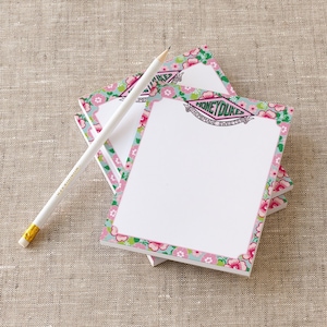 May include: A stack of floral patterned notepad paper with a pink and green border. The top sheet has the text "Honeydukes Homemade Sweets" in a green banner.