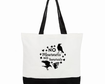 May include: White canvas tote bag with black handles and a black bottom. The bag has a black graphic design with the text "NO Mourners NO Funerals" and two black crow silhouettes.